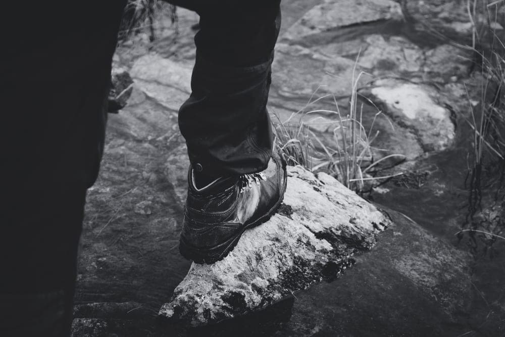 A hiking shoe stepping onto wet ground on a trail
